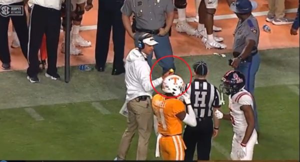 Lane Kiffin holds up a golf ball