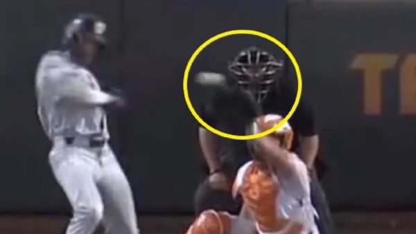 An umpire getting hit in the face mask