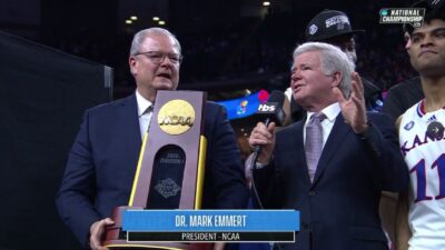 Mark Emmert holds a mic