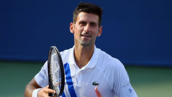 Novak Djokovic smiling while holding his raquet