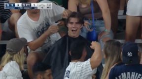 A Yankees fan getting a haircut from another fan in Yankee Stadium.