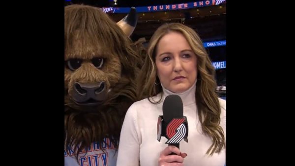 Mascot standing behind reporter