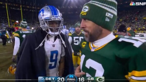 Aaron Rodgers points to his jersey