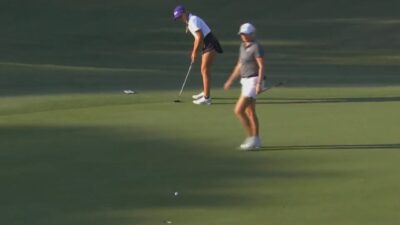 A golfer walks in front of a putt