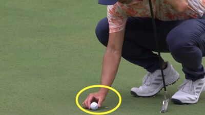 Collin Morikawa moves his ball away from his ball marker