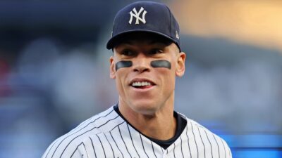 Aaron Judge smiles while wearing a Yankees cap