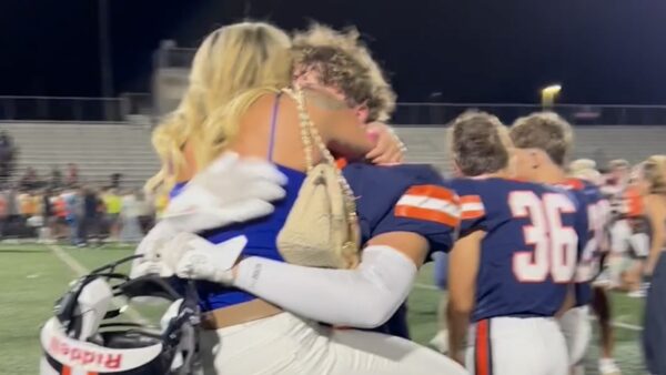 A mother hugs her son after a high school football game