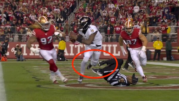 Ravens quarterback Lamar Jackson trips over referee Alex Moore against the 49ers