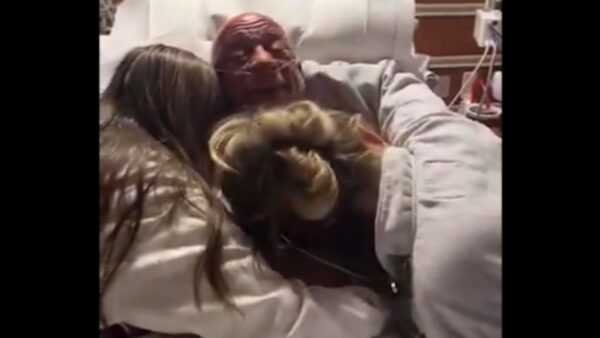 Mark Coleman hugs his daughters in a hospital bed