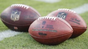 Some NFL footballs on the ground logo