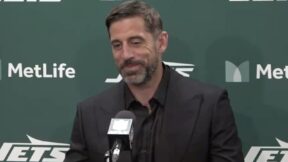 Aaron Rodgers smirks during a press conference