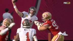 Baker Mayfield making a pass with Nick Bosa trying to tackle him