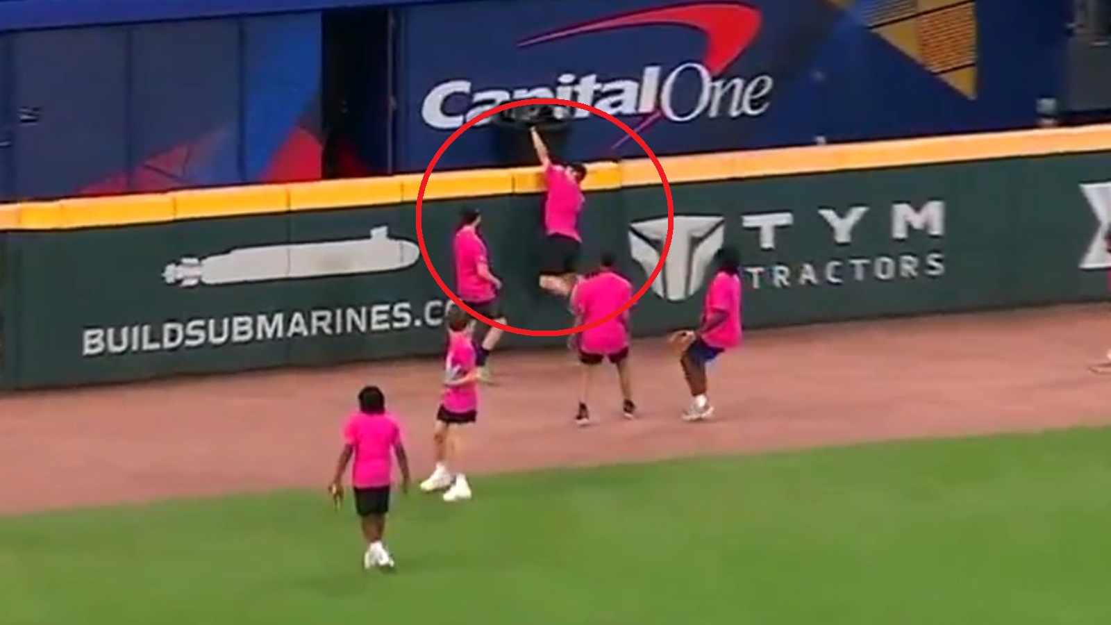A kid in the outfield making a catch at the wall