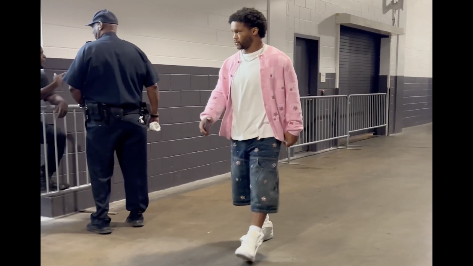 Kyler Murray wears a pink sweater and jean shorts