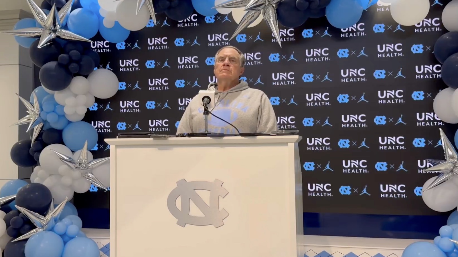 Bill Belichick underneath a balloon arch at his first North Carolina postgame press conference