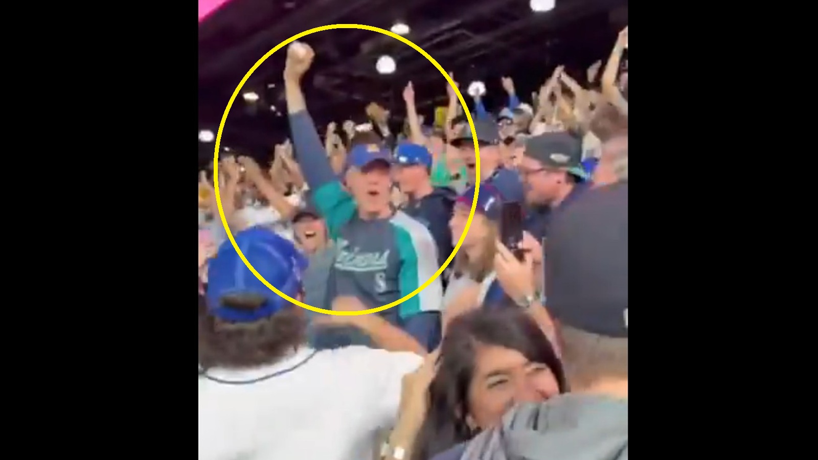 A Mariners fan holding up a home run ball