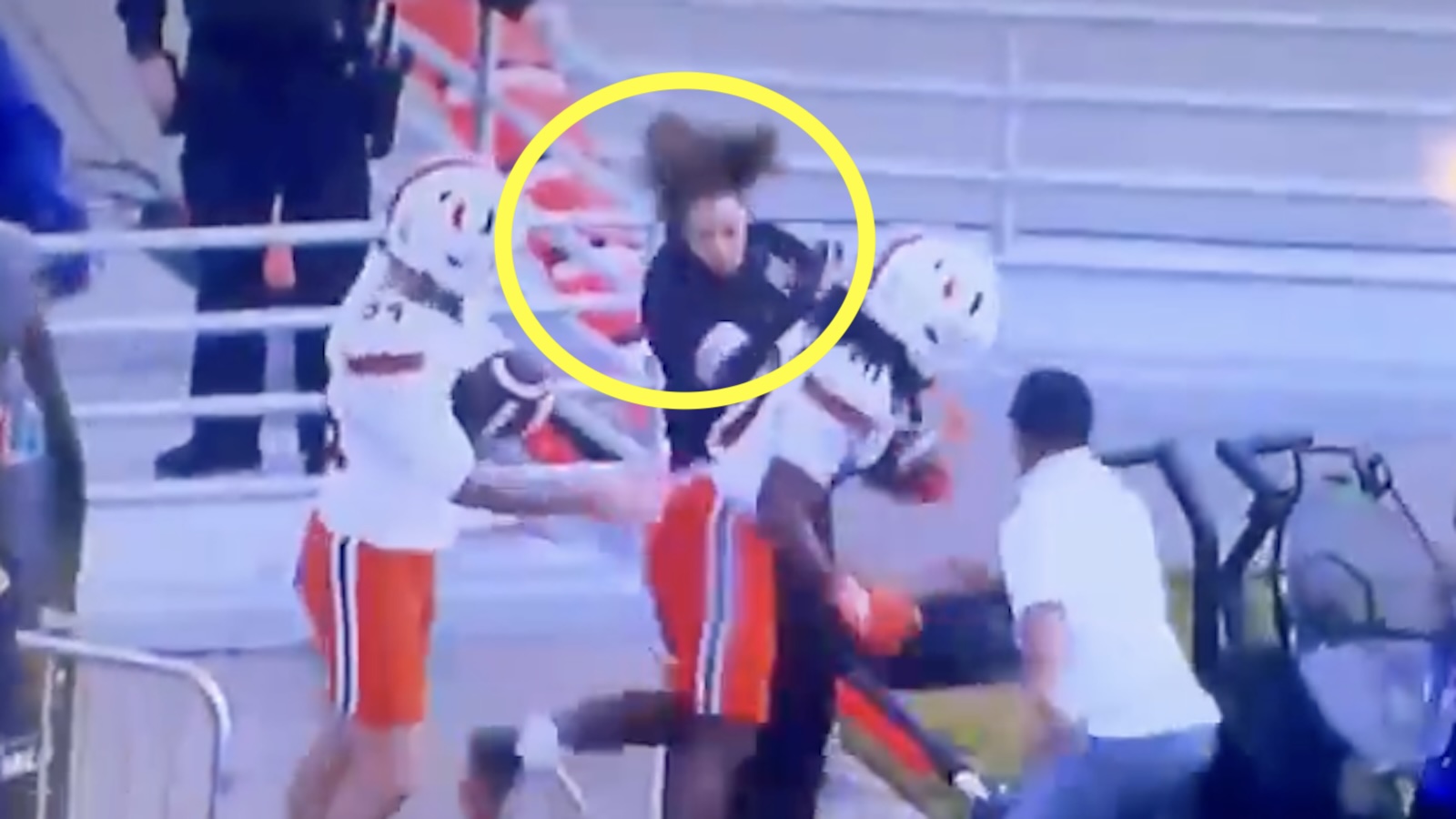 A woman is bulldozed by a Miami player on the sideline
