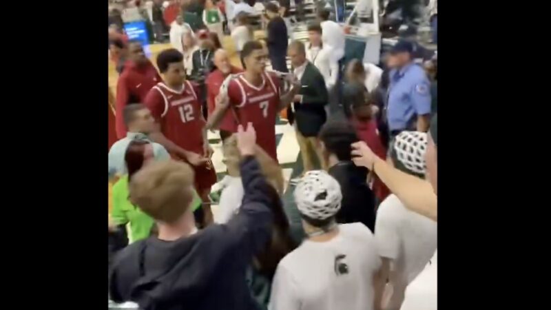 Arkansas senior Trevon Brazile holds a towel as Michigan State fans taunt him