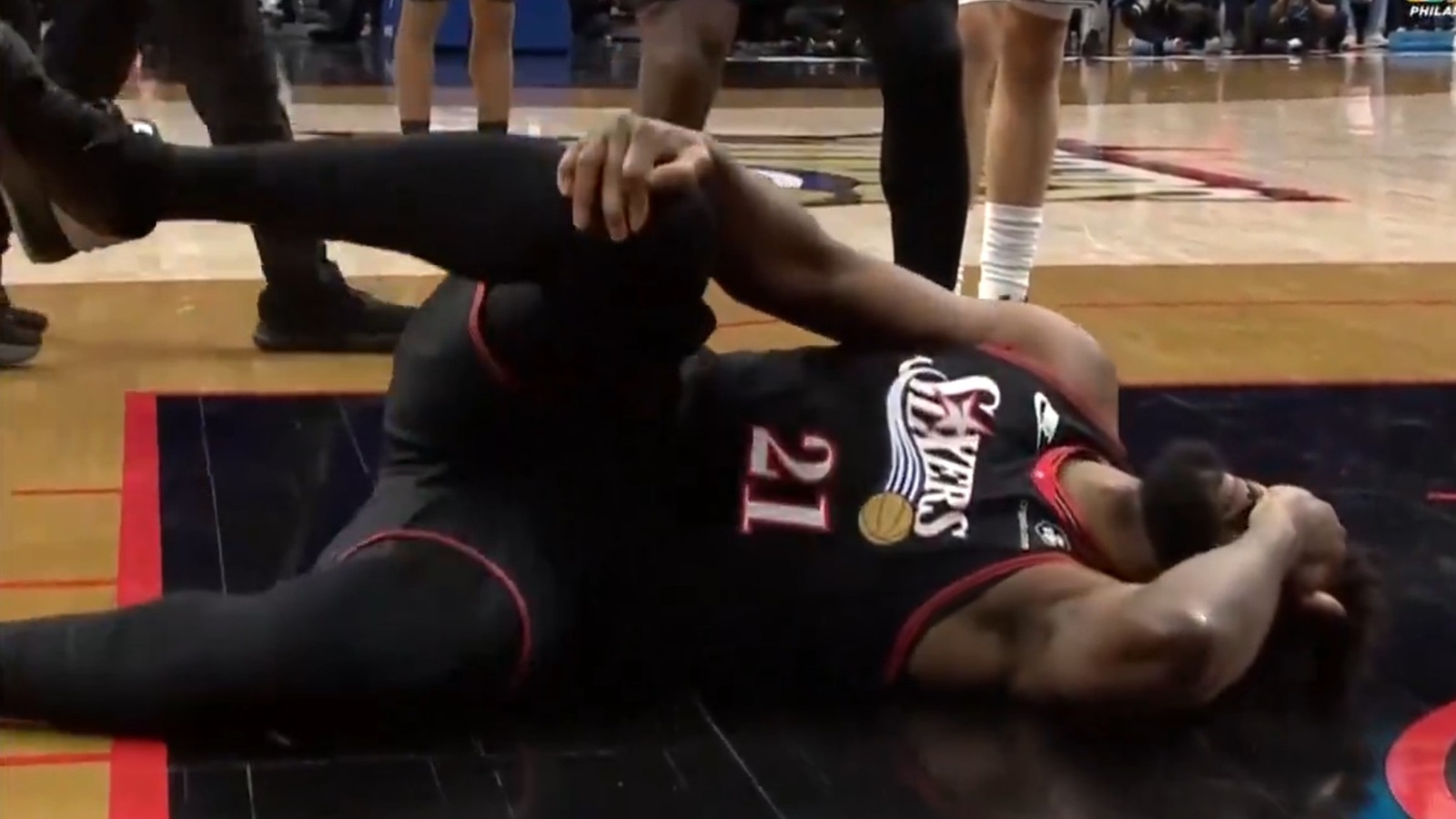 Joel Embiid holding onto his knee in pain
