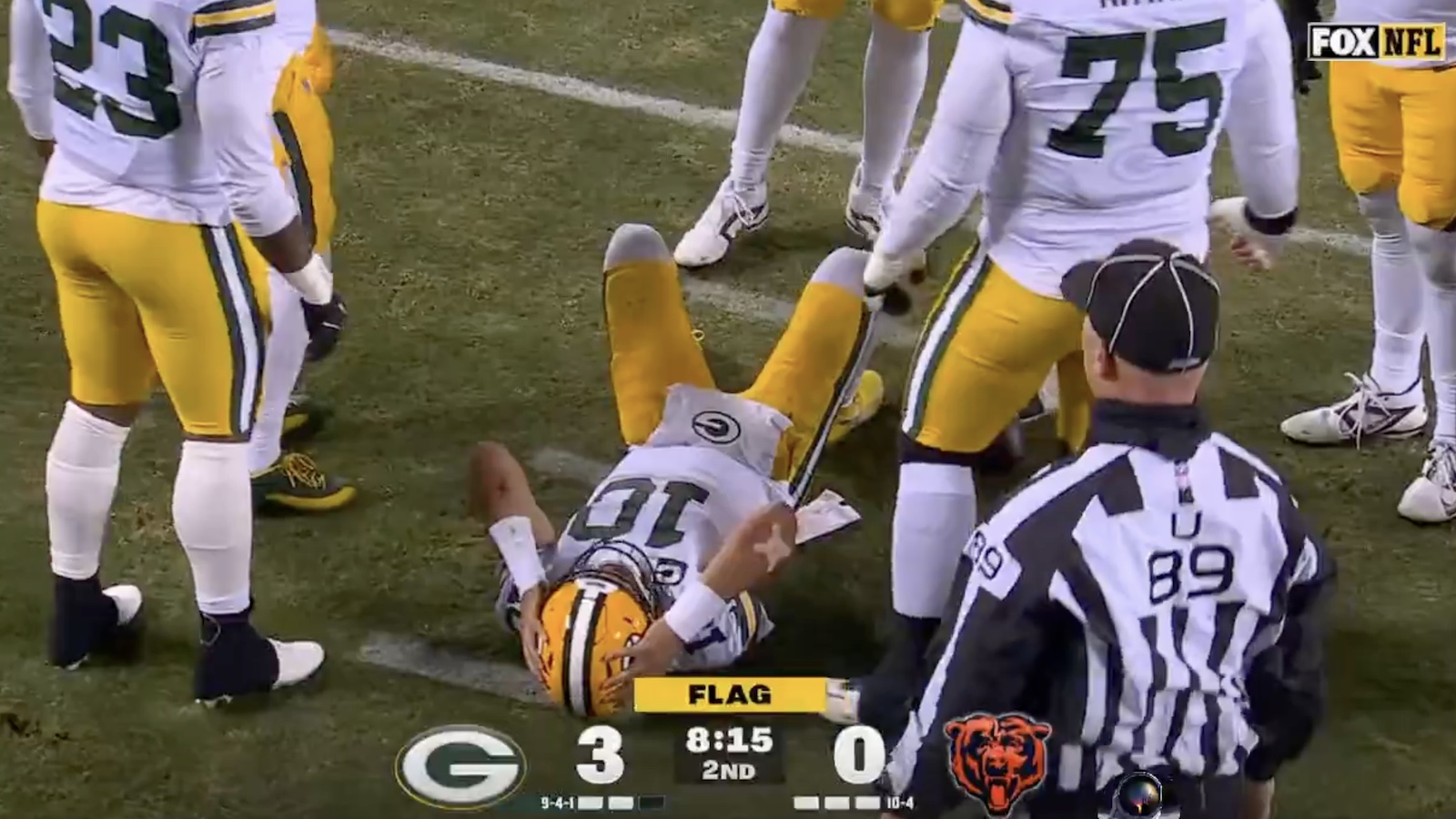 Packers QB Jordan Love on the ground grabbing his helmet