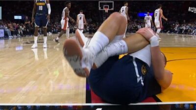 Nikola Jokic holding onto his knee in pain
