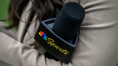 A woman holding a mic with the NBC Sports logo on it