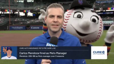 Mr. Met dancing behind a Mets reporter talking about the firing of manager Carlos Mendoza