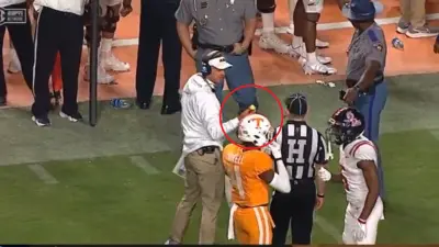 Lane Kiffin holds up a golf ball