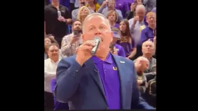 Brian Kelly holds a microphone