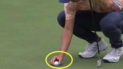 Collin Morikawa moves his ball away from his ball marker
