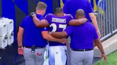 JK Dobbins is helped off the field with an injury