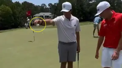 A golfer holds out a ball