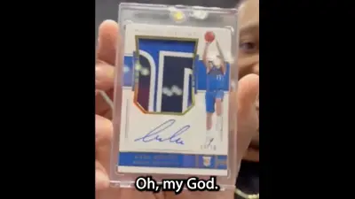 Grant Williams holding up a Dallas Mavericks Luka Doncic rookie patch auto (RPA)