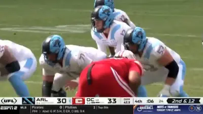 A quarterback takes a snap in a UFL game